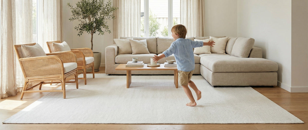 Un niño corriendo sobre una gran alfombra clara, en un salón de lino beige