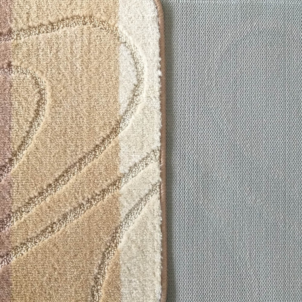 Tapis moelleux aux motifs ondulés beige, crème et brun, bordé à droite par une surface gris clair texturée