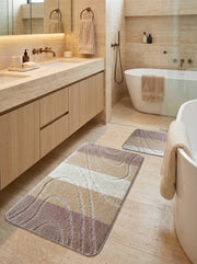 Tapis rectangulaire doux aux motifs de bandes beige clair, blanc crème et taupe, ornés d'ondes en relief, dans une salle de bain