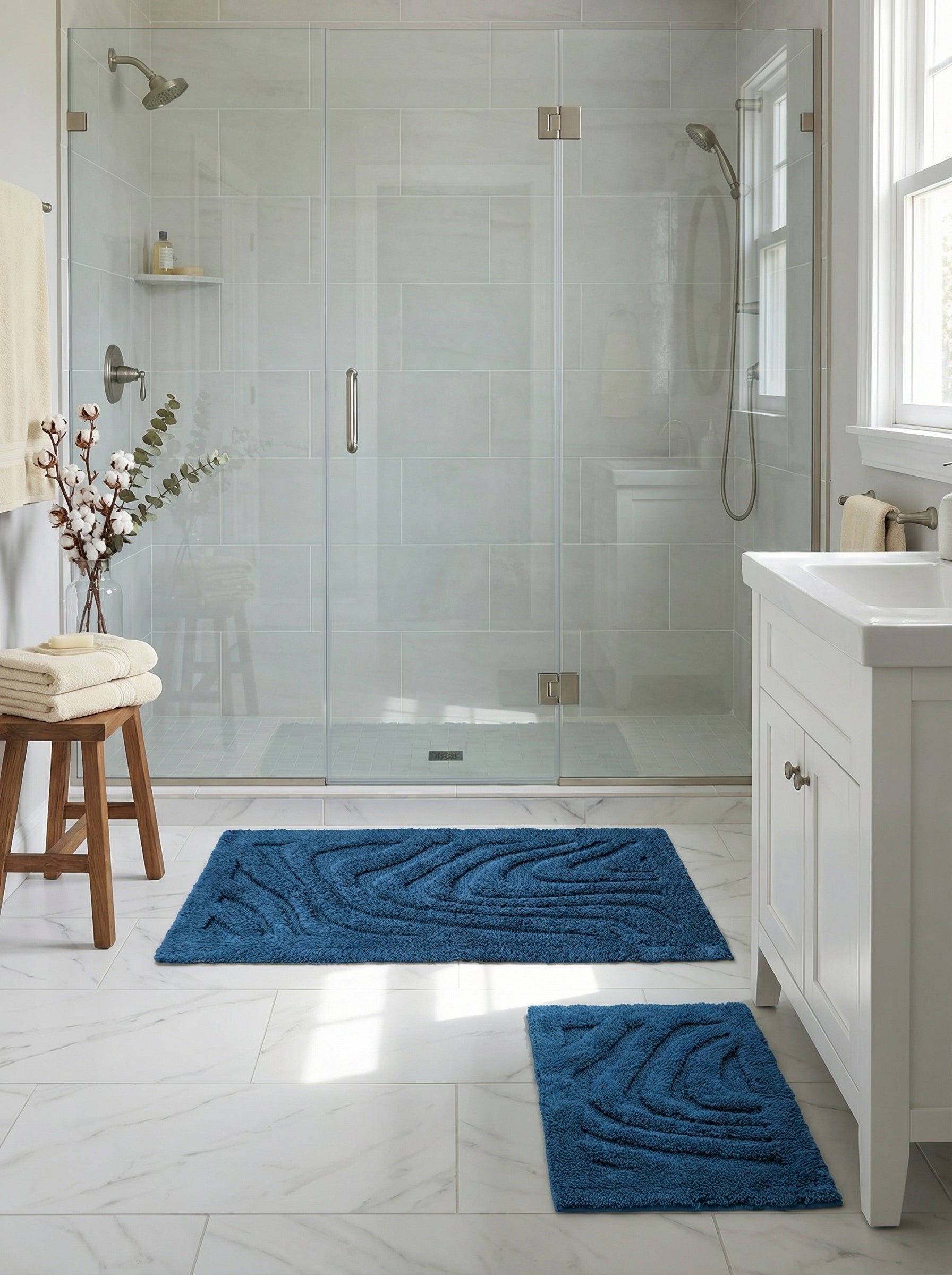 Deux tapis de bain bleus rectangulaires avec des motifs ondulés en relief sur un sol carrelé clair dans une salle de bain moderne