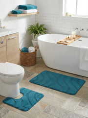 Deux tapis de bain éponge turquoise aux motifs ondulés en relief, un rectangulaire et un en U, dans une salle de bain