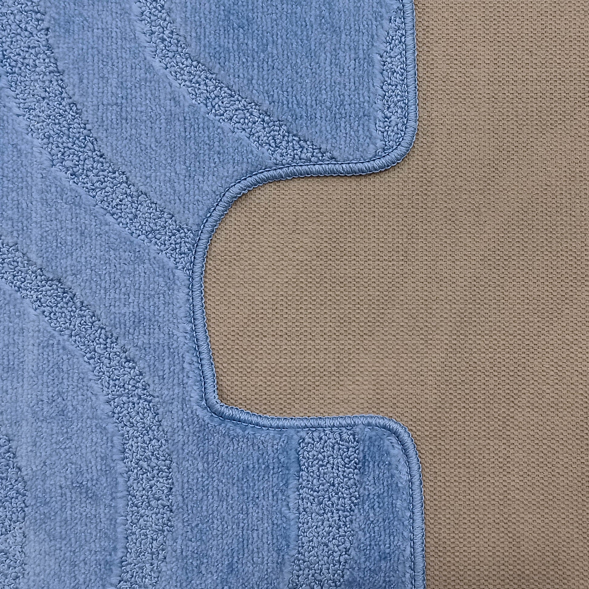 Tapis bleu ciel à la texture douce et bouclée, avec des motifs en relief et un bord ondulé cousu sur un fond tissé beige