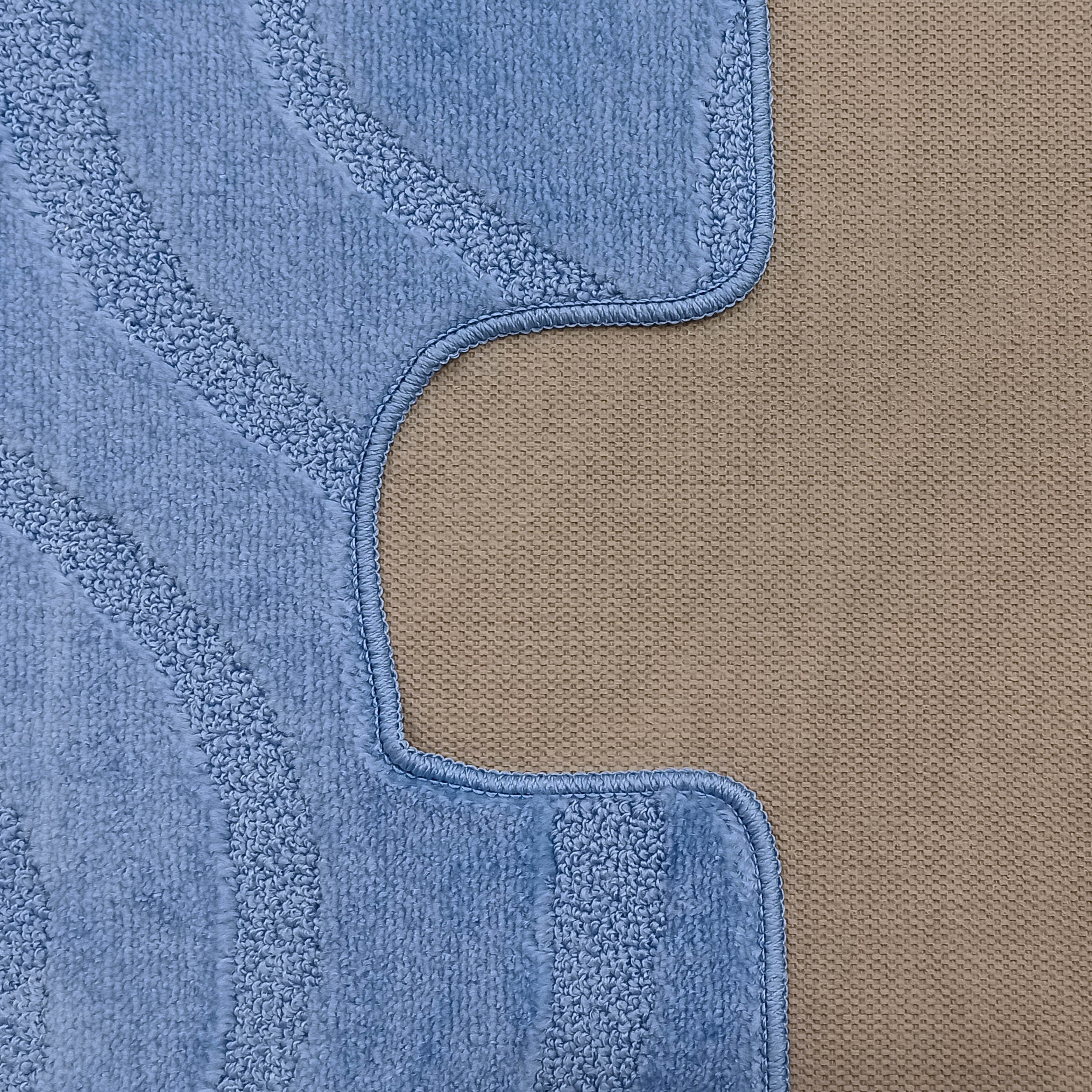 Tapis bleu ciel à la texture douce et bouclée, avec des motifs en relief et un bord ondulé cousu sur un fond tissé beige