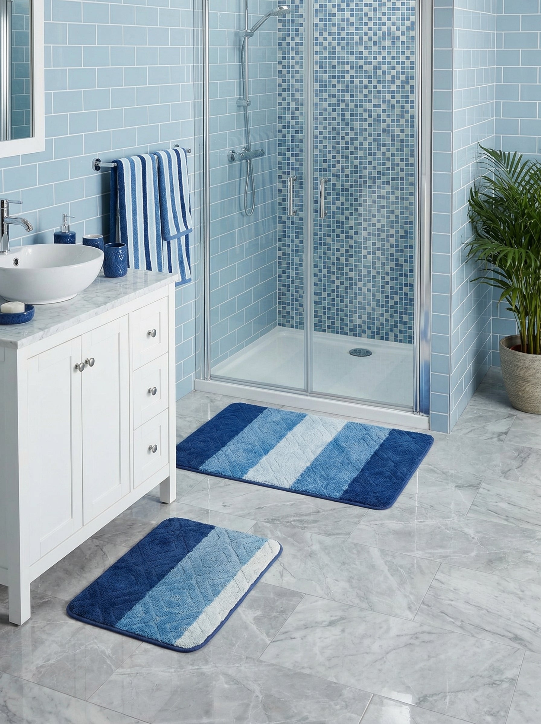 Deux tapis de bain rayés bleu foncé, moyen, clair et blanc avec des motifs en losanges sur un sol carrelé gris clair dans une salle de bain