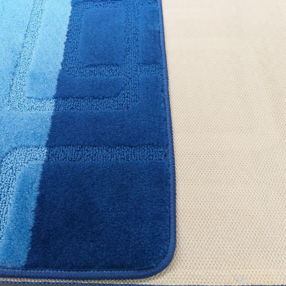 Tapis bleu à motifs géométriques et bandes de différentes nuances, avec son envers beige finement tissé apparent