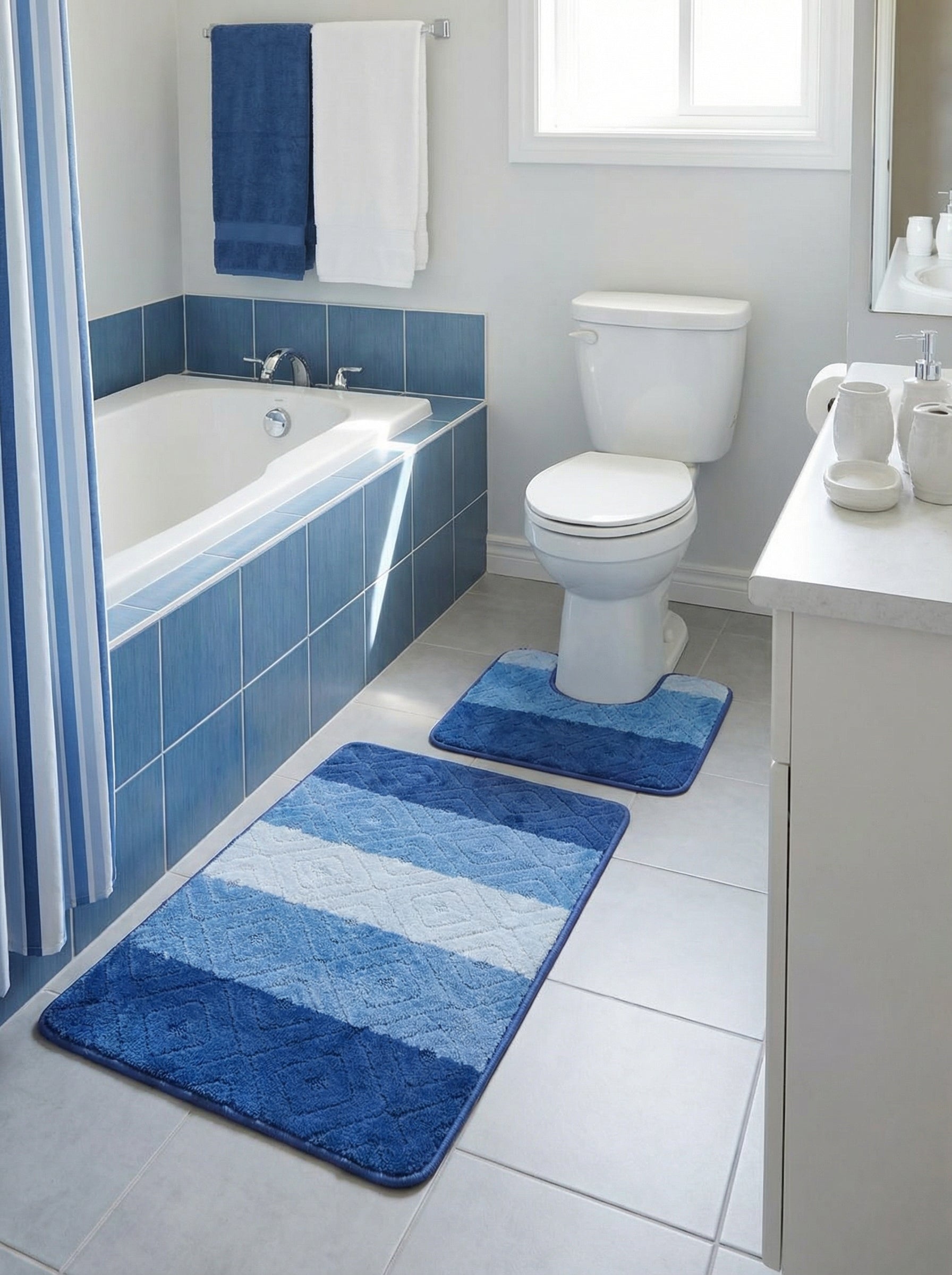 Deux tapis de bain bleus dégradés, l'un rectangulaire et l'autre en forme de U, avec motifs losanges discrets, posés dans une salle de bain