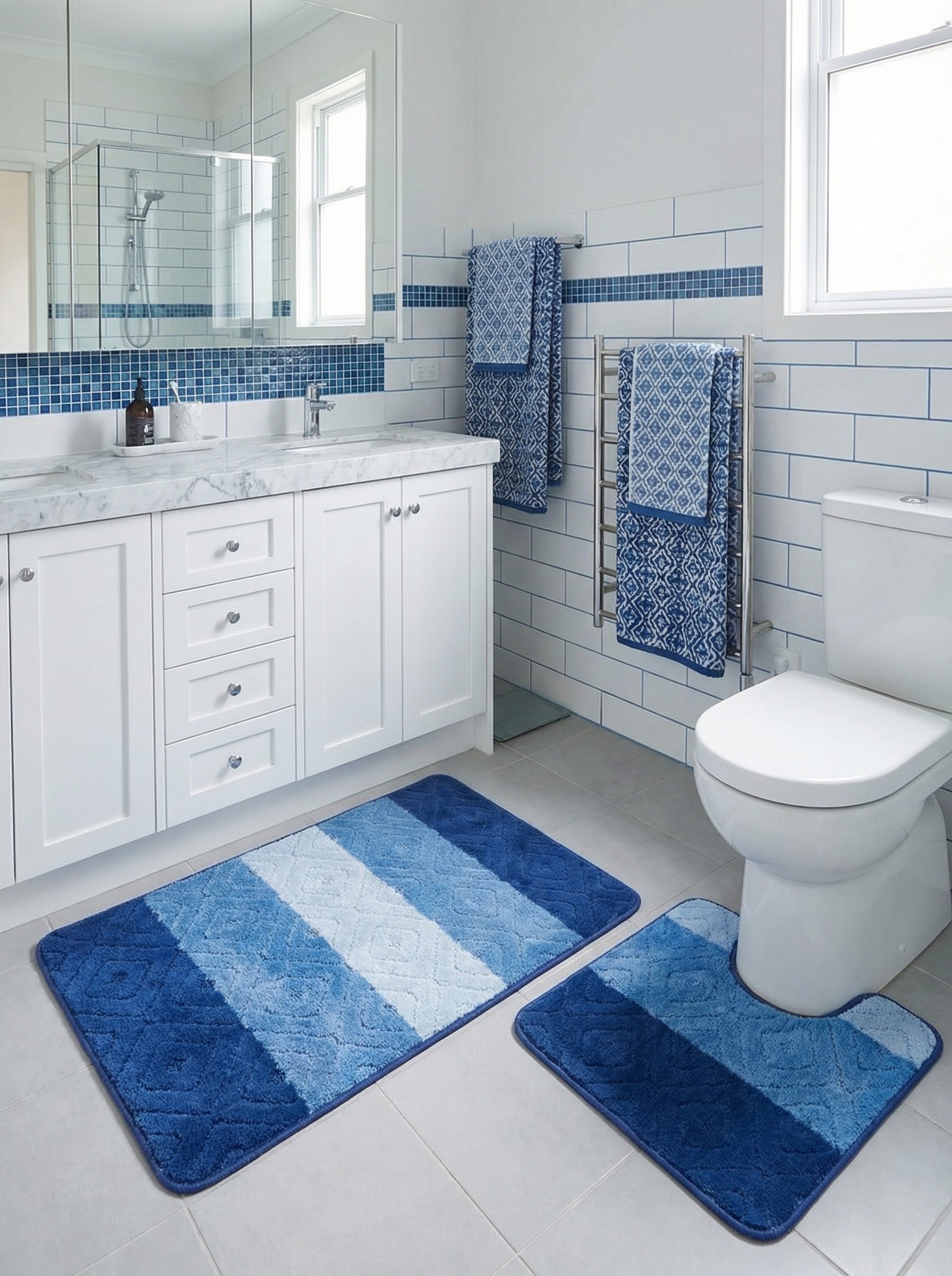 Deux tapis de bain moelleux, un rectangulaire et un contour de WC, à rayures diagonales bleues et blanches dans une salle de bain