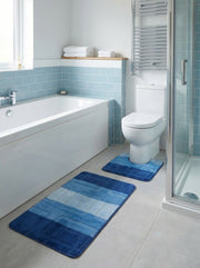 Deux tapis de bain bleus en tissu, l'un rectangulaire et l'autre en U, avec des blocs de nuances de bleu, dans une salle de bain