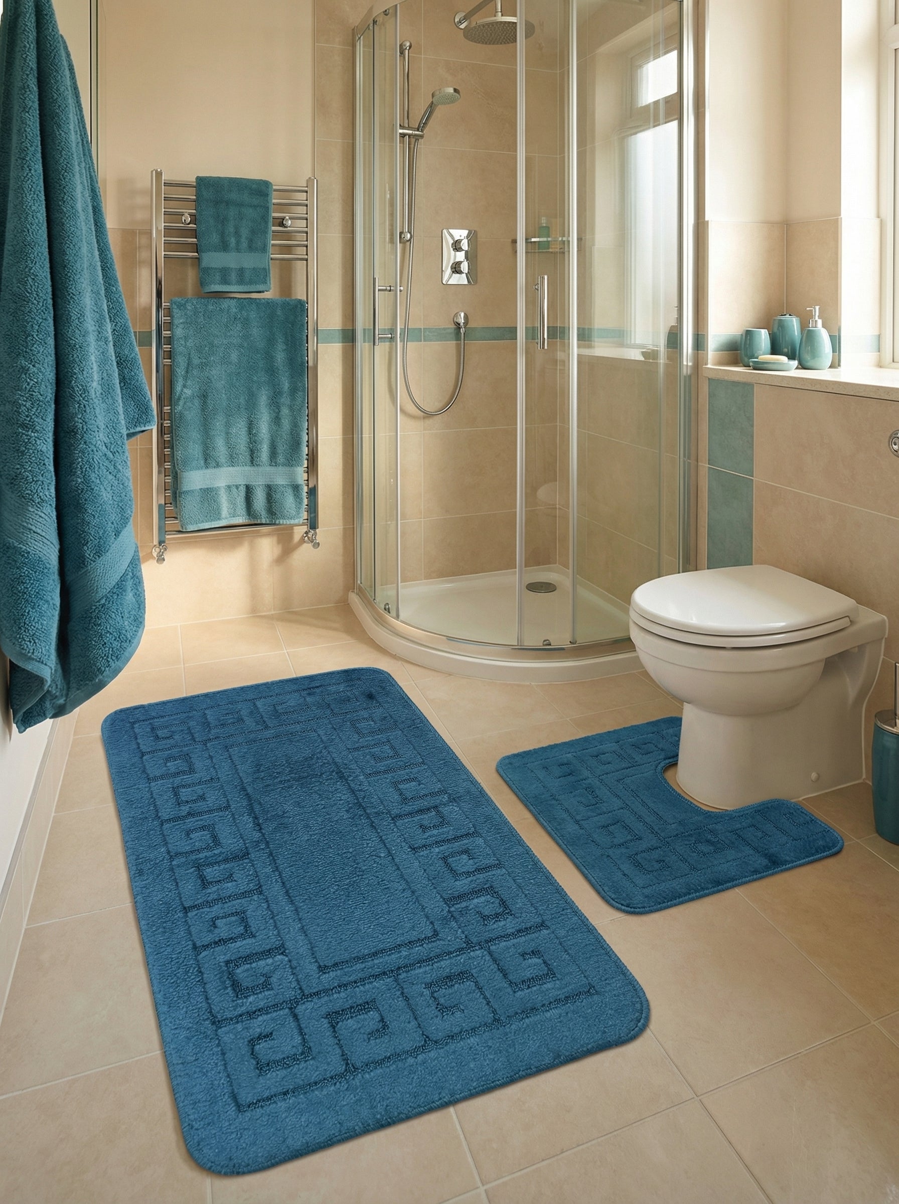Ensemble de deux tapis de bain bleu sarcelle, à motifs grecs en relief, sur le sol carrelé d'une salle de bain