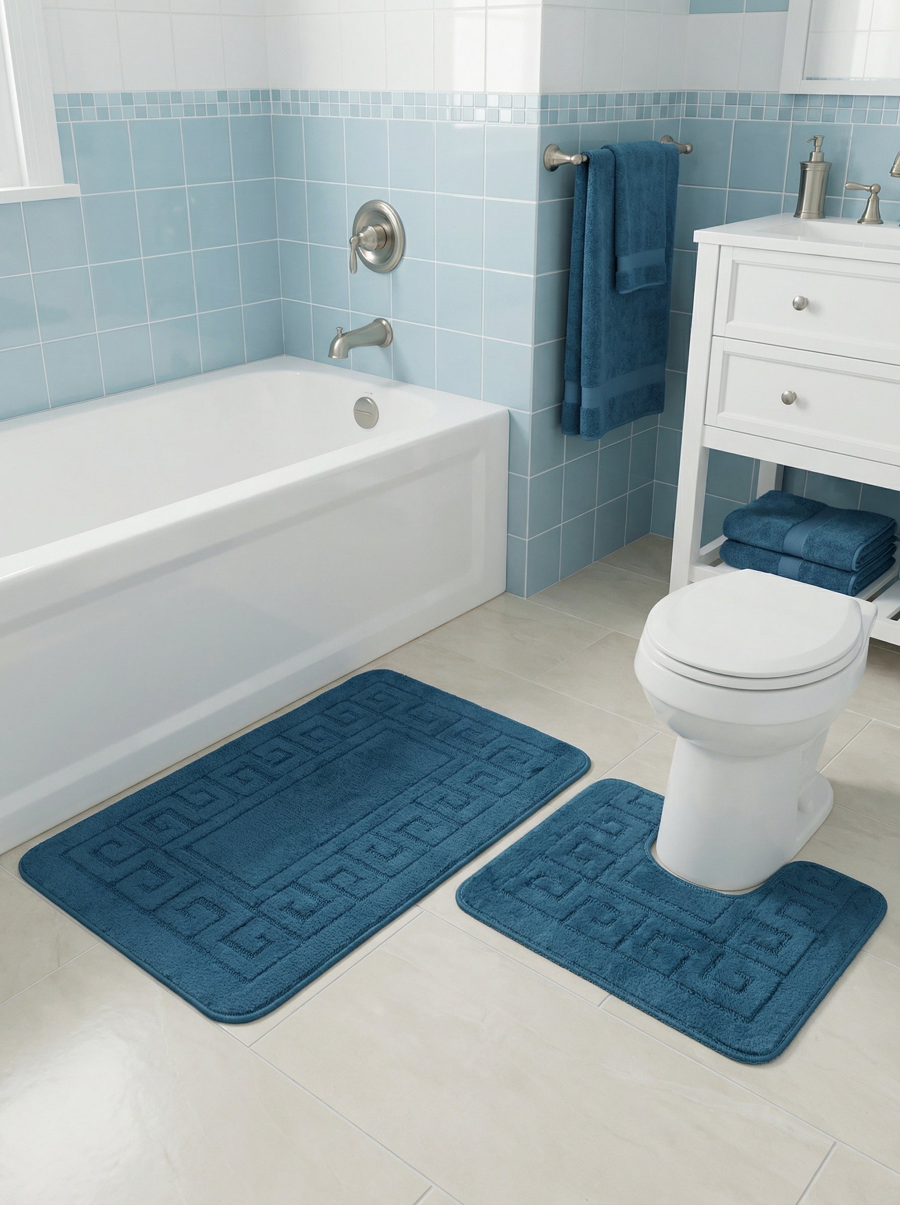 Deux tapis de bain doux bleu foncé à motifs géométriques en relief, l'un rectangulaire et l'autre en U, dans une salle de bain