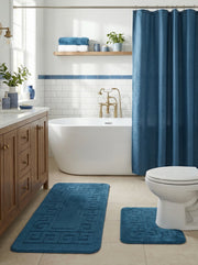 Deux tapis de bain moelleux bleu canard avec motifs géométriques en relief posés au sol d'une salle de bain