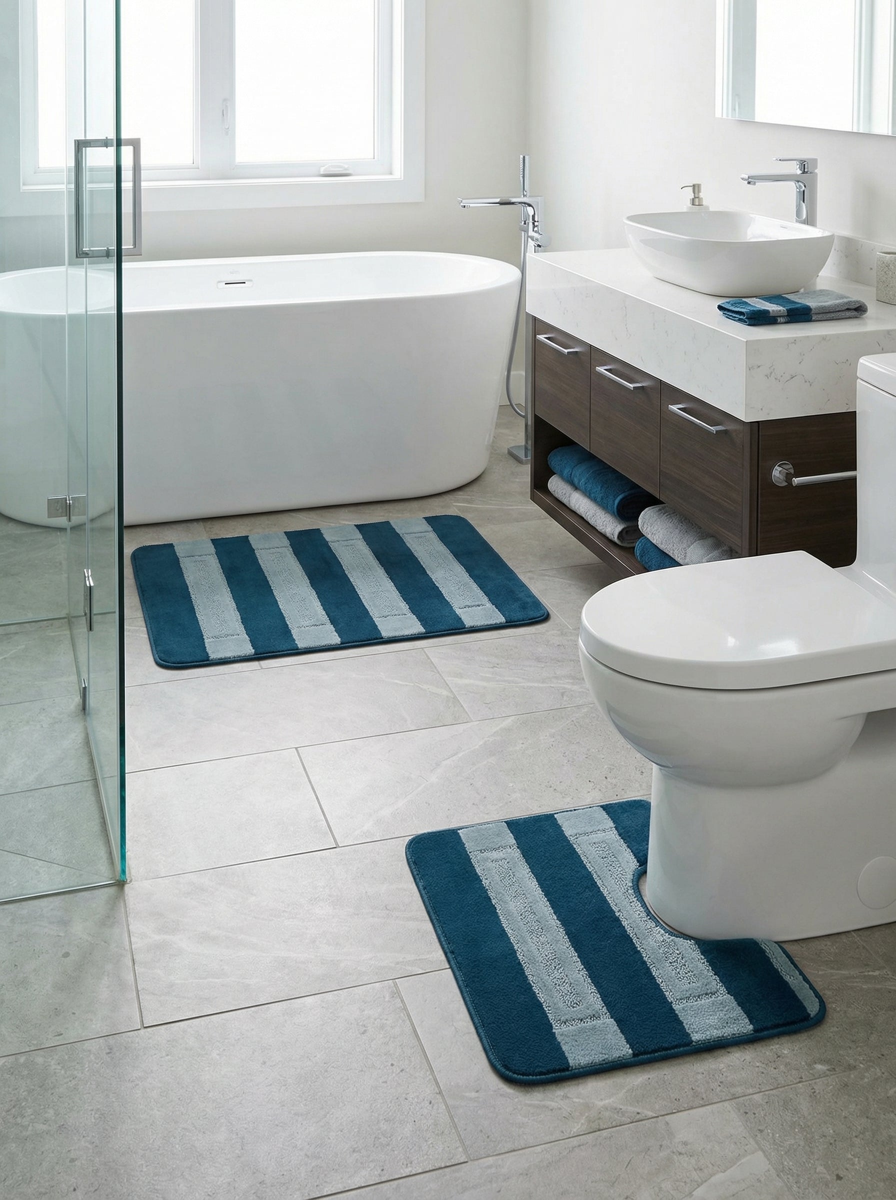Deux tapis de bain rayés bleu pétrole et gris clair sur un sol carrelé dans une salle de bain moderne
