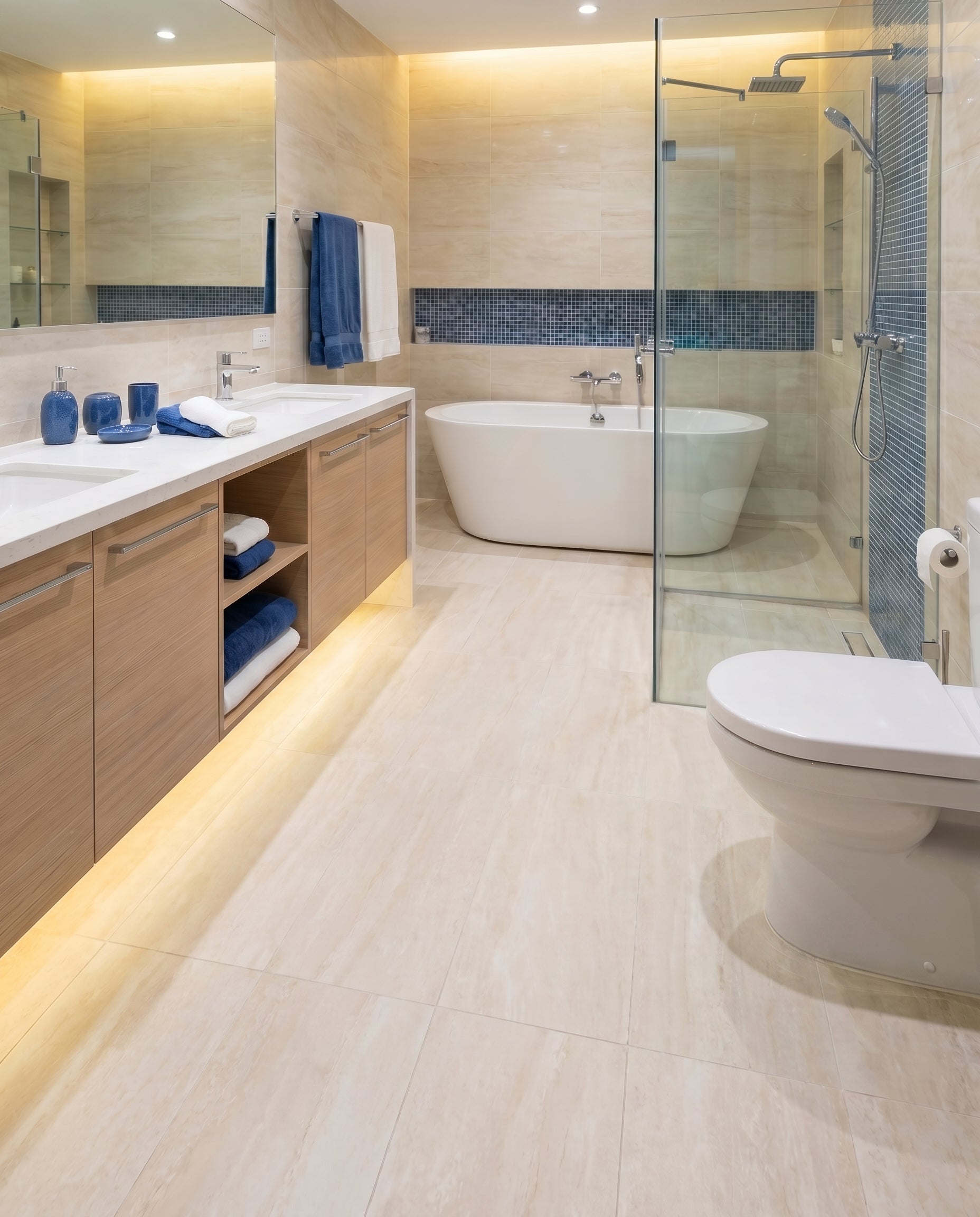 Salle de bain moderne avec sol en grands carreaux beiges clairs, un meuble double lavabo, une baignoire blanche et une douche vitrée