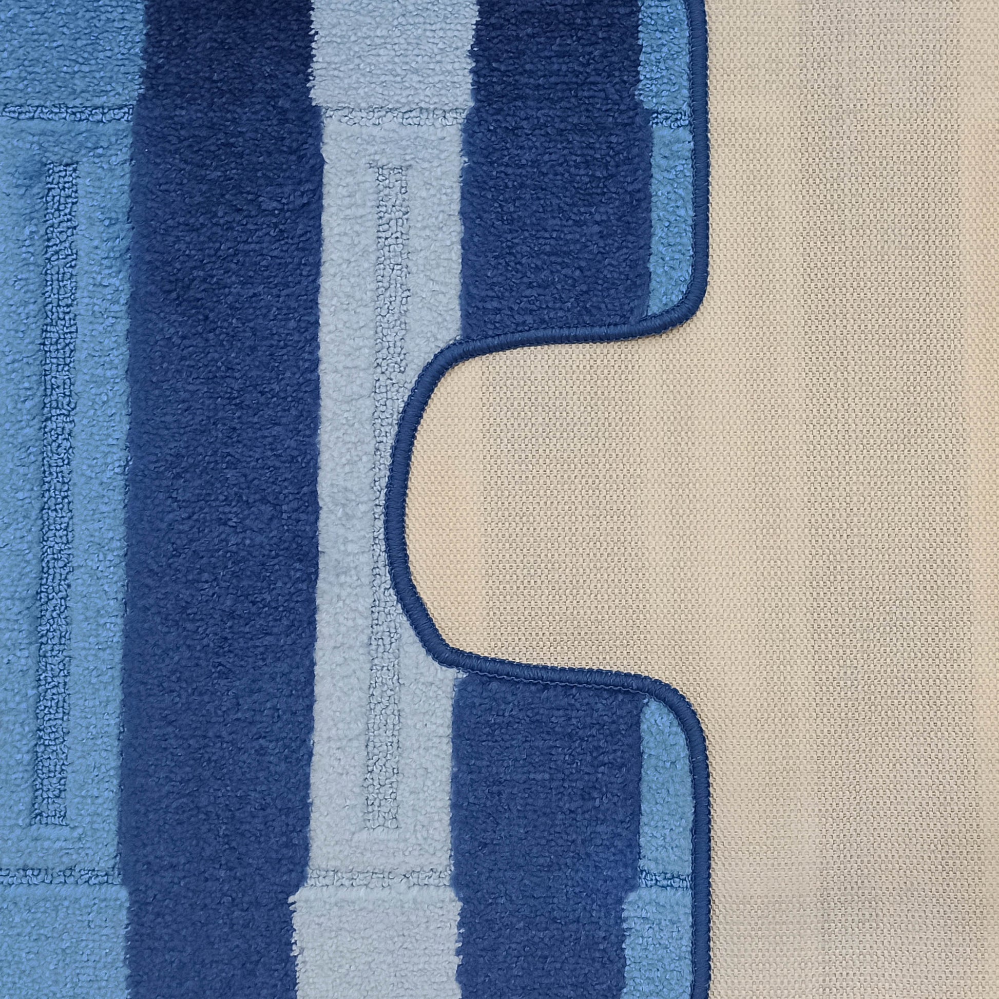 Tapis à rayures bleues foncées et claires, texturé façon bouclé, bordé d'un liseré bleu foncé et d'une section beige tissée