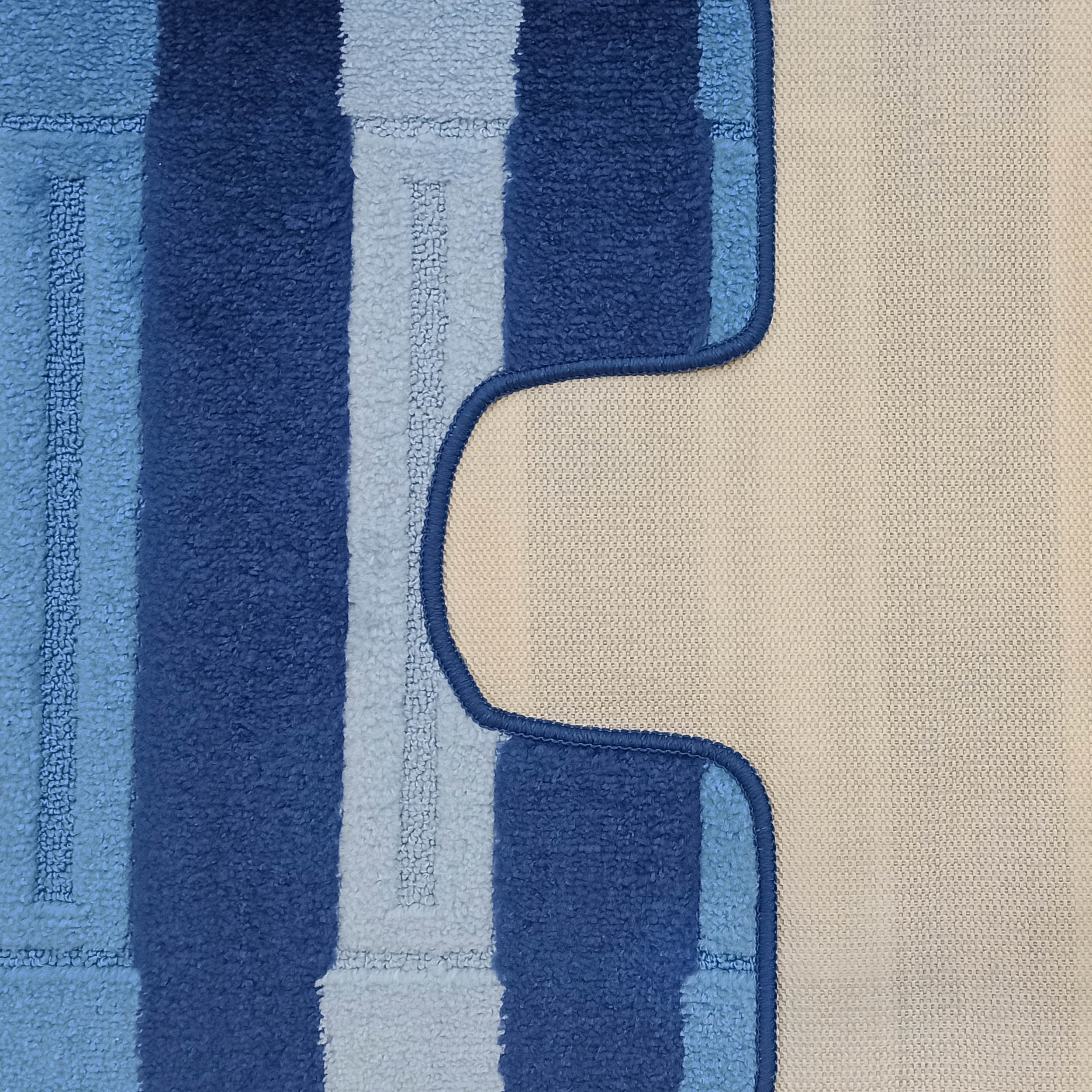 Tapis à rayures bleues foncées et claires, texturé façon bouclé, bordé d'un liseré bleu foncé et d'une section beige tissée