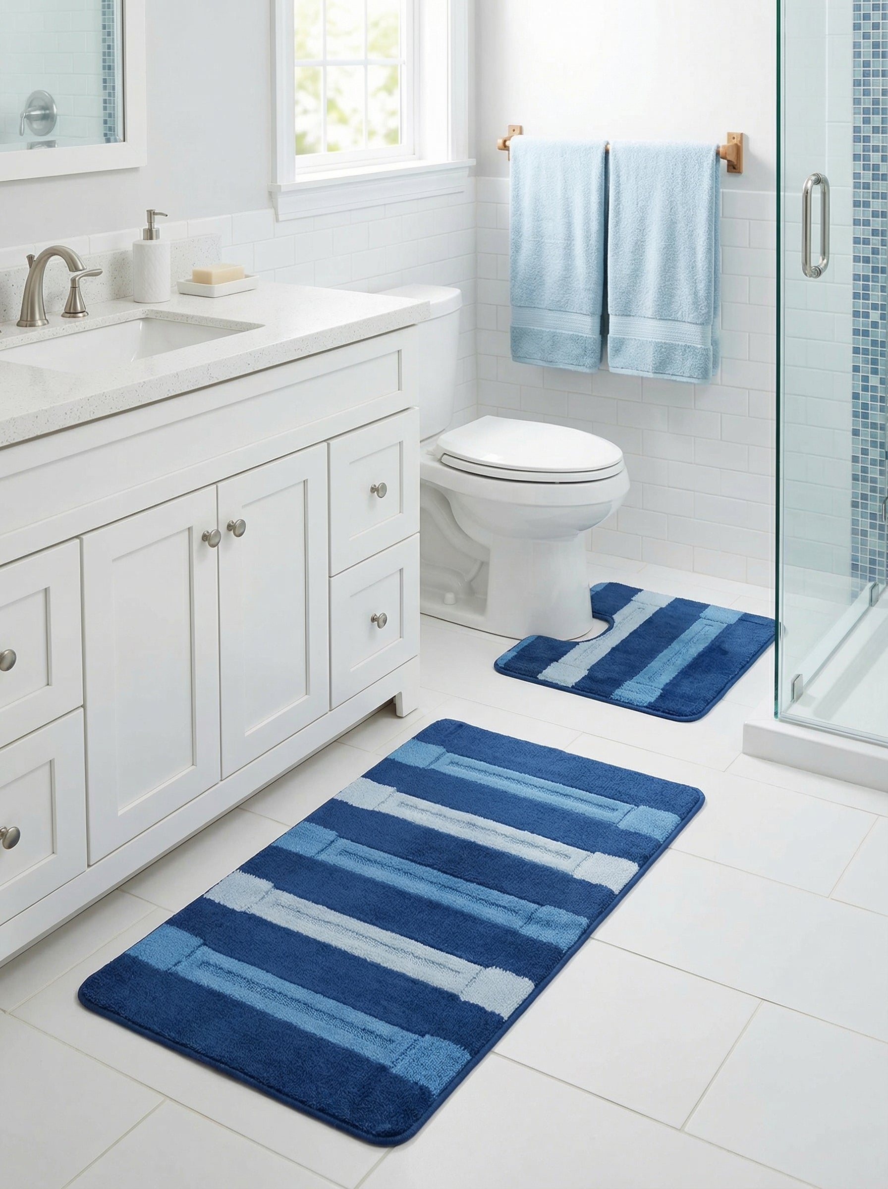 Deux tapis en tissu doux à rayures bleues variées et blanches, l'un rectangulaire, l'autre en U, dans une salle de bain claire