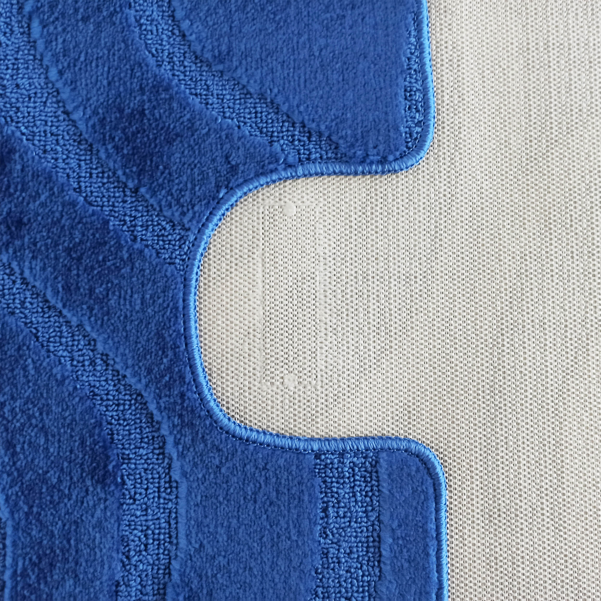 Tapis bleu texturé avec motifs de vagues en relief et un contour découpé, laissant apparaître un dessous en textile tissé clair