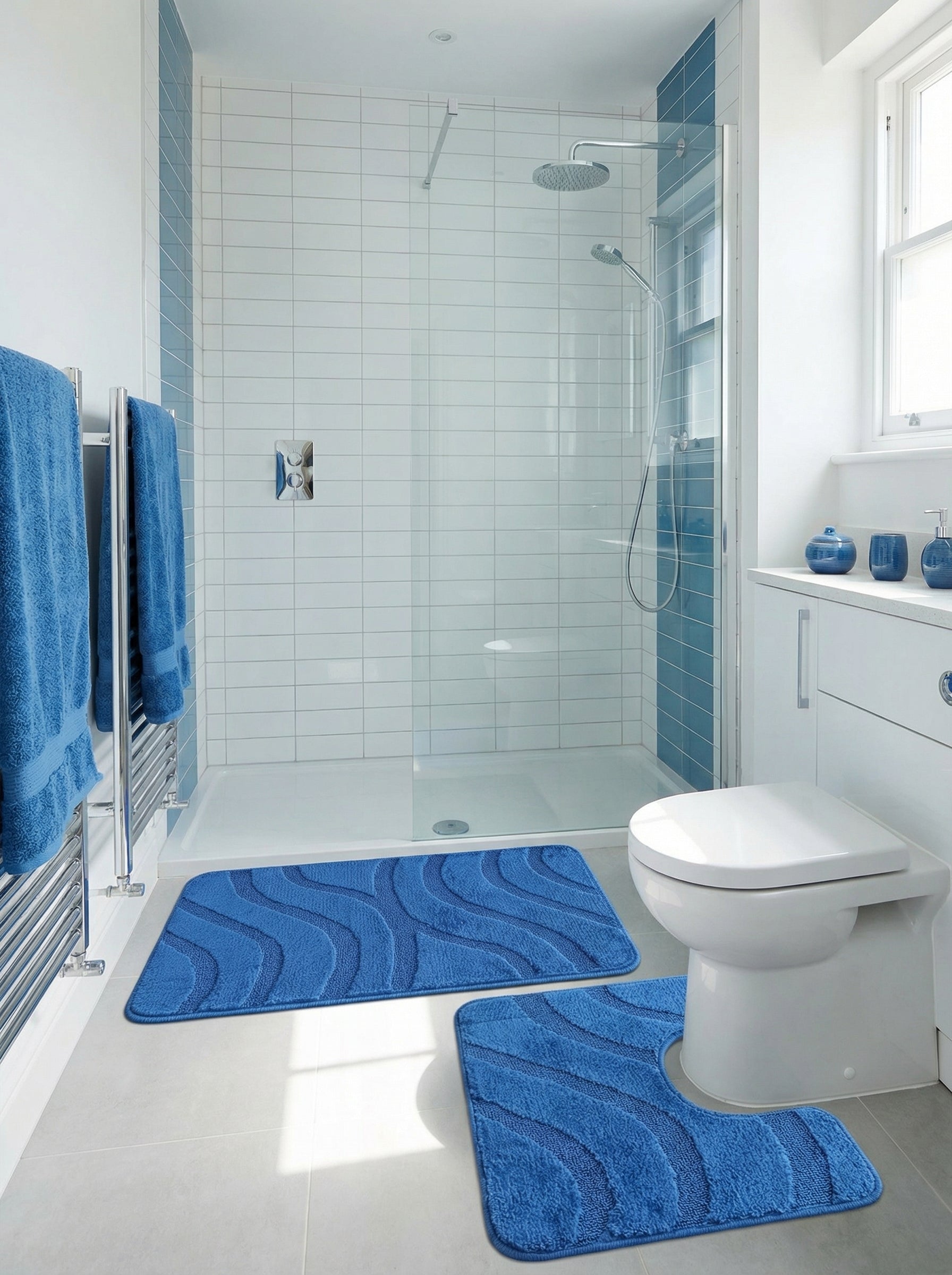 Deux tapis de bain en microfibre bleu vif avec des motifs de vagues en relief, l'un rectangulaire, l'autre en U, dans une salle de bain moderne