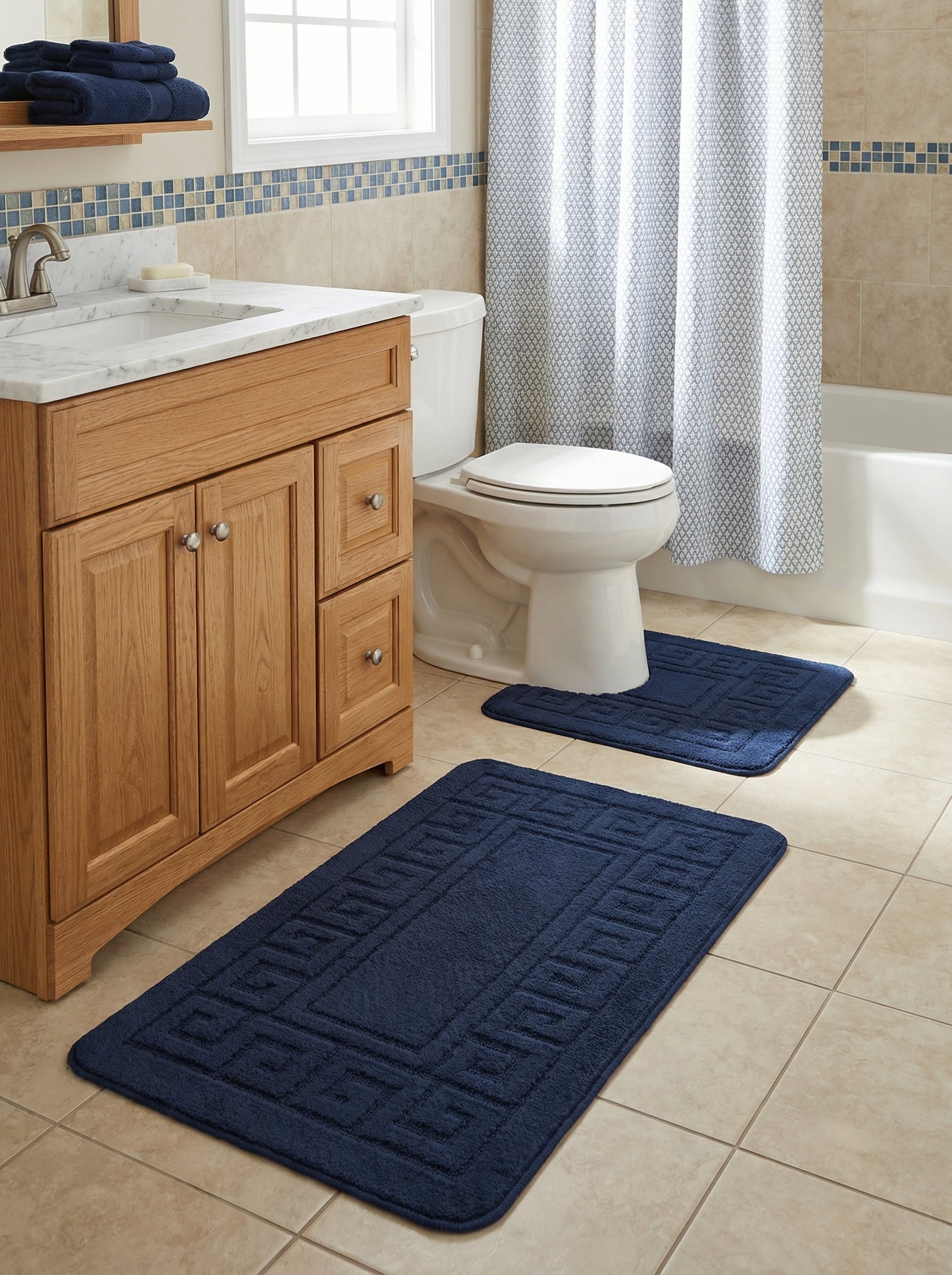 Deux tapis de bain bleu marine en tissu éponge avec un motif géométrique en relief sur les bordures, dans une salle de bain carrelée