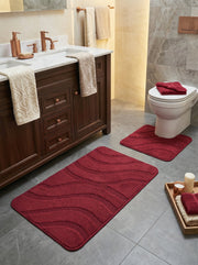 Tapis de bain rouge vif texturé à motifs ondulés et un tapis contour toilette assorti, dans une salle de bain