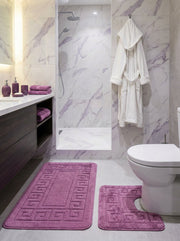 Tapis de bain prune en éponge, l'un rectangulaire, l'autre en U, tous deux avec un motif grec en relief, dans une salle de bain