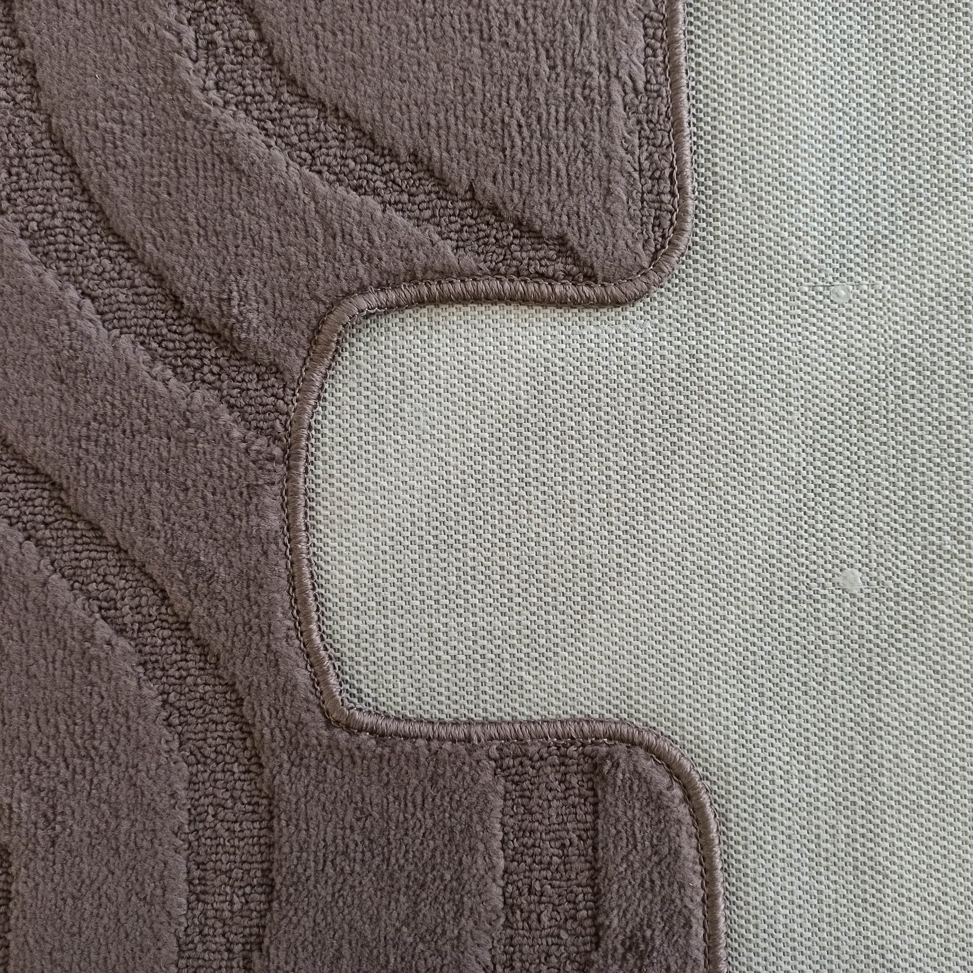 Gros plan d'un tapis en bouclette marron-gris avec motifs ondulés en relief et envers antidérapant tissé clair