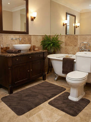 Deux tapis de bain marron foncé moelleux, un rectangulaire et un en forme de U, ornés de motifs ondulés, dans une salle de bain