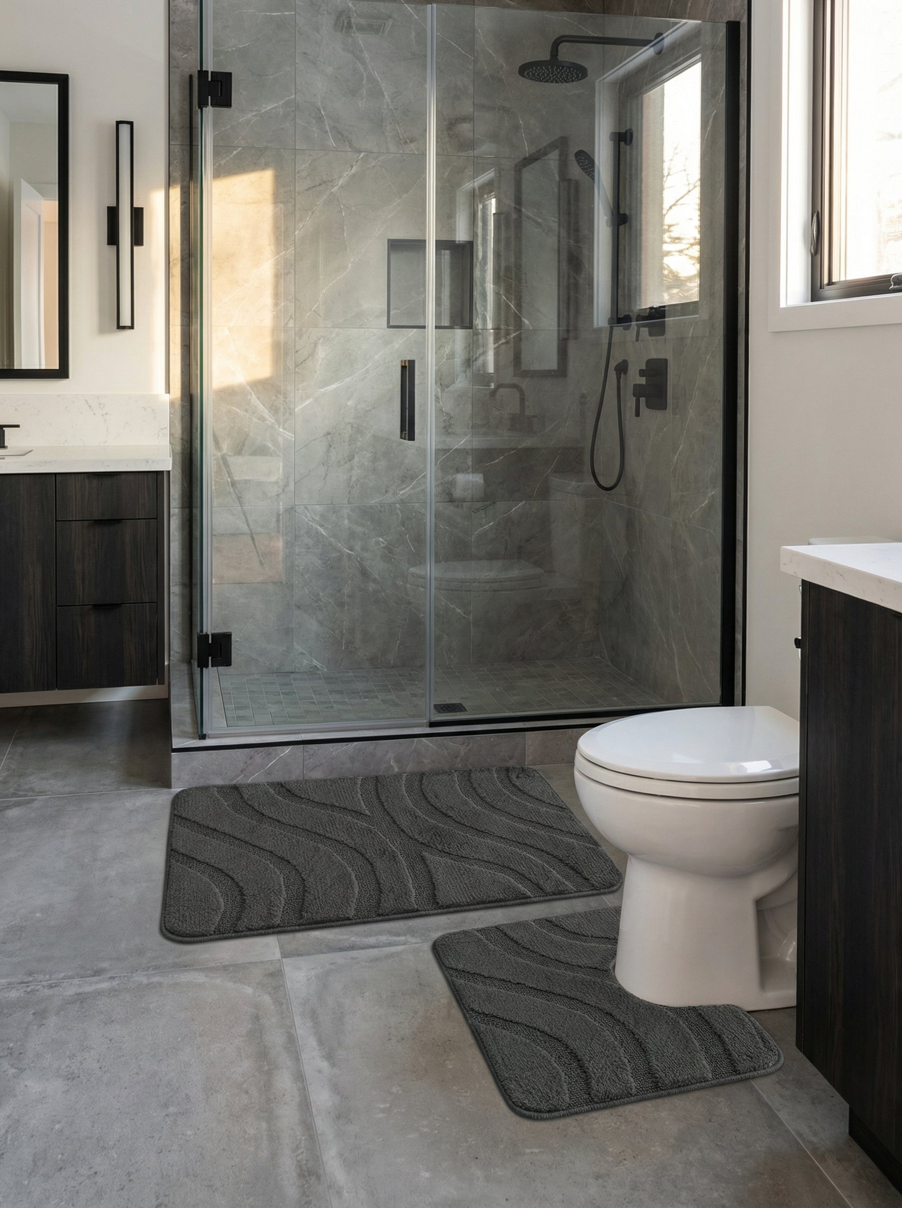 Deux tapis de bain gris anthracite moelleux avec des motifs de vagues en relief, posés sur le sol d'une salle de bain moderne