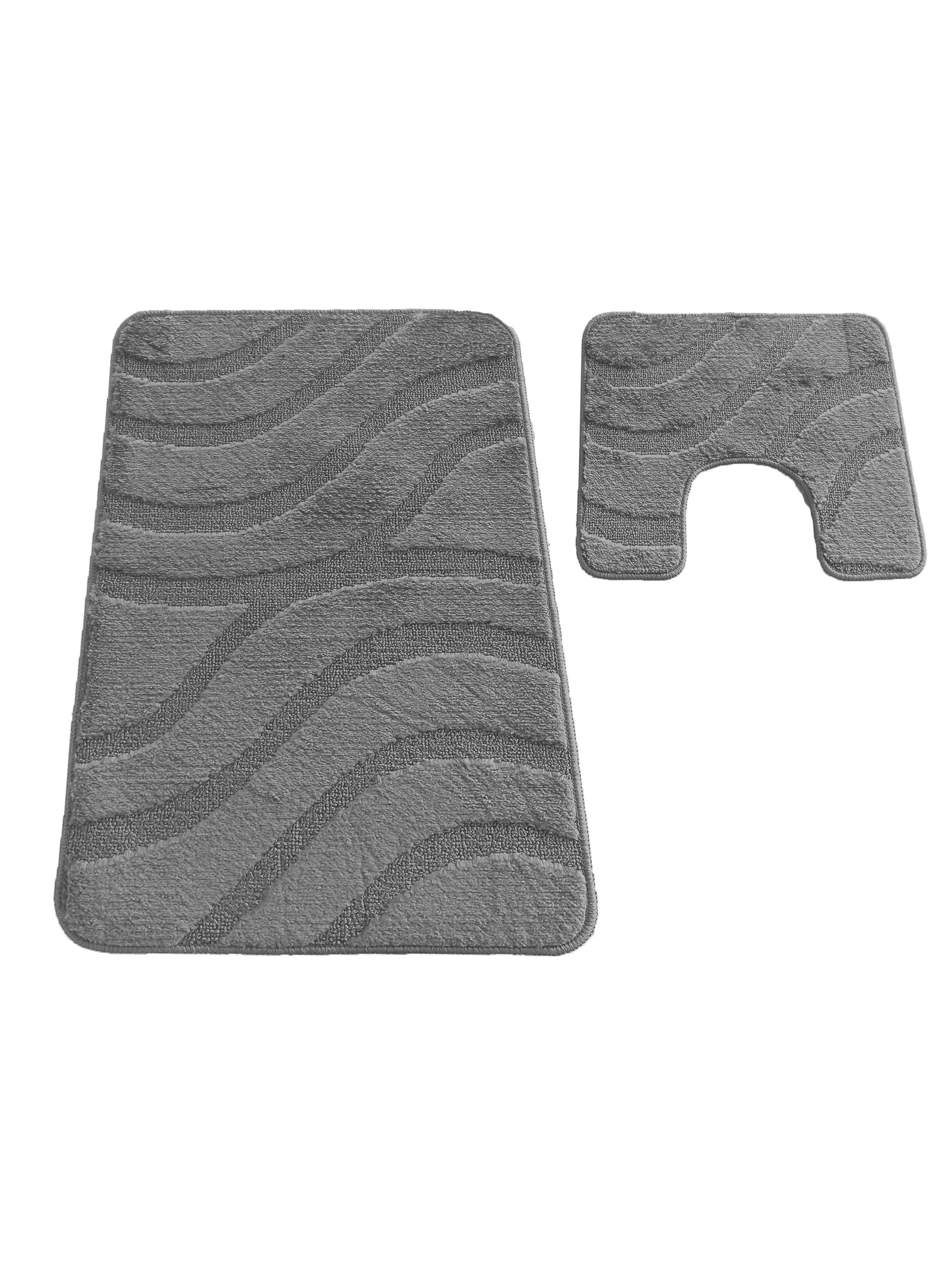 Deux tapis de bain gris moelleux, ornés de motifs de vagues texturées. Un tapis rectangulaire et un tapis en forme de U