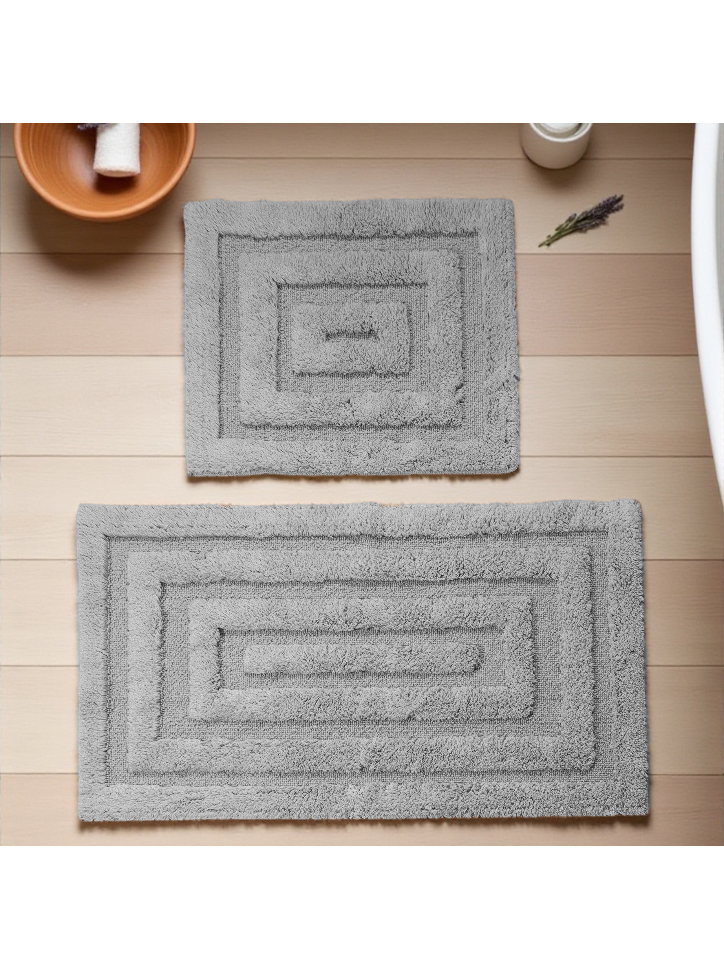 Deux tapis gris moelleux à motifs rectangulaires concentriques, posés sur un sol en bois clair