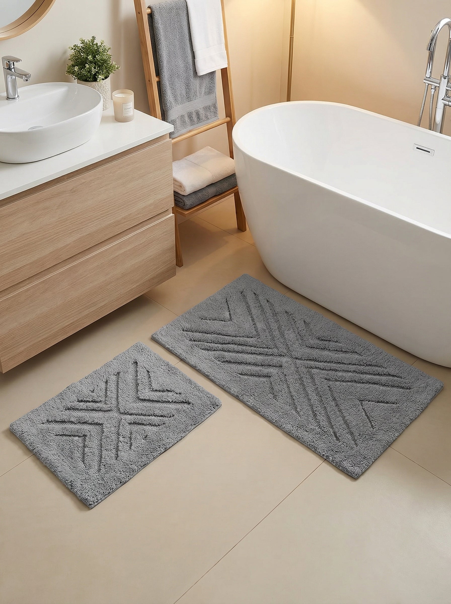 Deux tapis de bain rectangulaires gris clair en bouclette, avec des motifs géométriques en relief, dans une salle de bain moderne