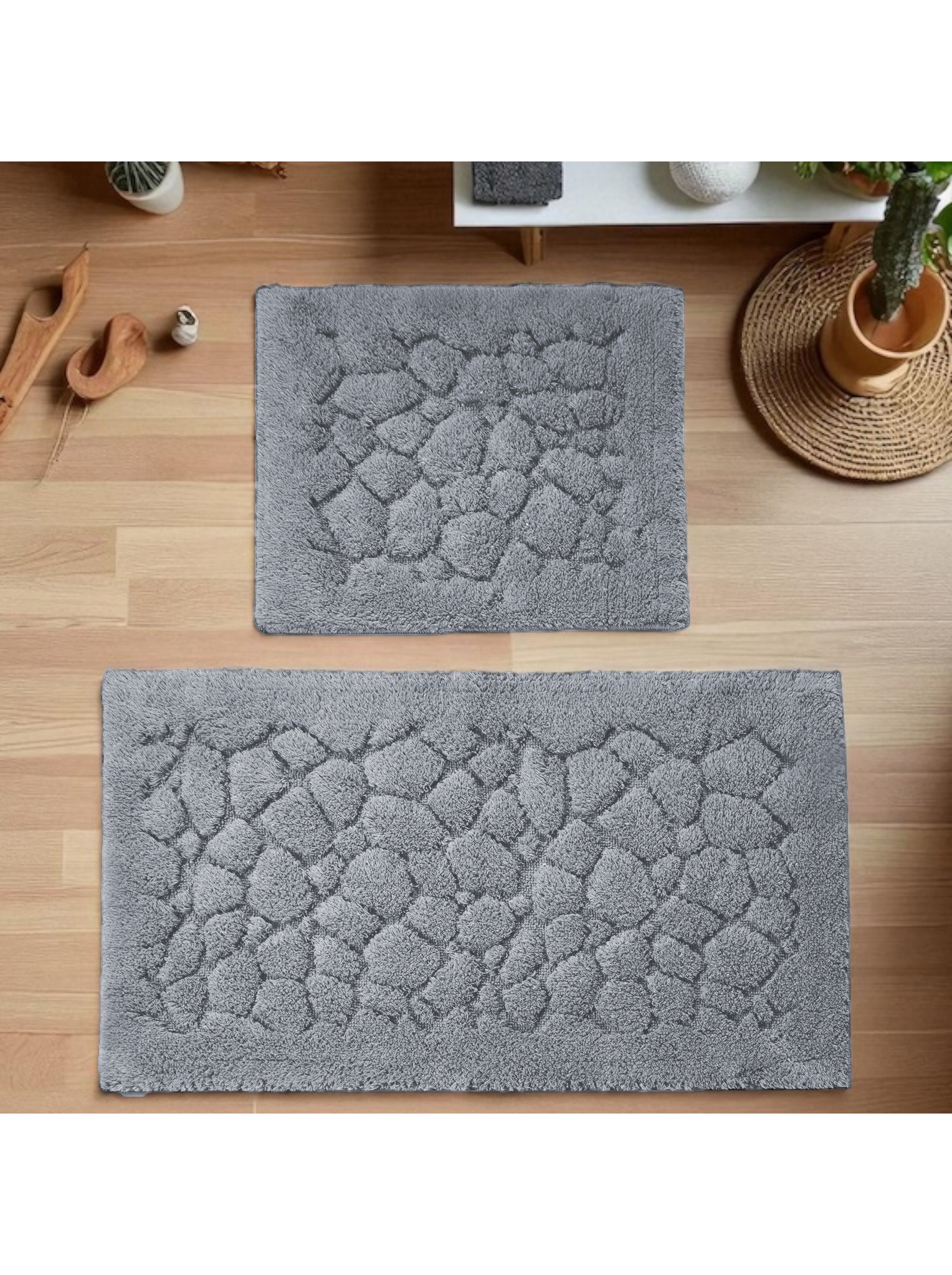 Ensemble de deux tapis gris à poils longs sur un parquet clair, présentant un motif en relief de galets