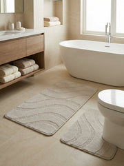 Un ensemble de tapis de bain beige en bouclette, orné de motifs de vagues en relief, décore une salle de bain moderne