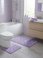 Deux tapis de bain en tissu doux mauve clair, présentant des motifs ondulés en relief, sont au sol d'une salle de bain moderne