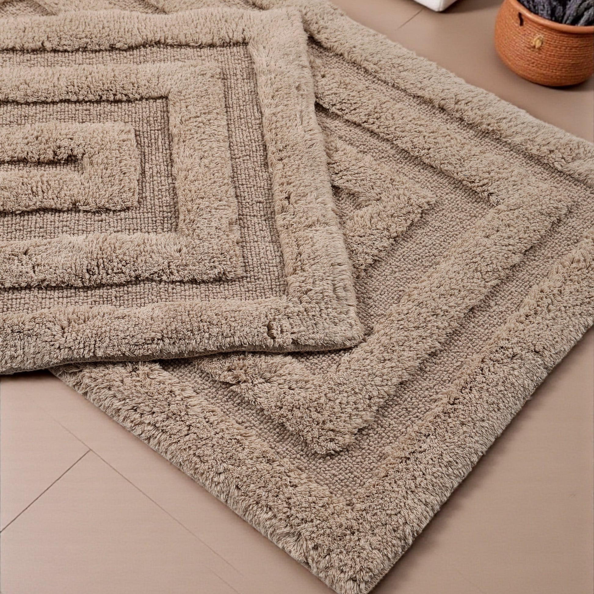 Tapis beige clair en matière douce bouclée, avec des motifs géométriques en relief formant des carrés concentriques