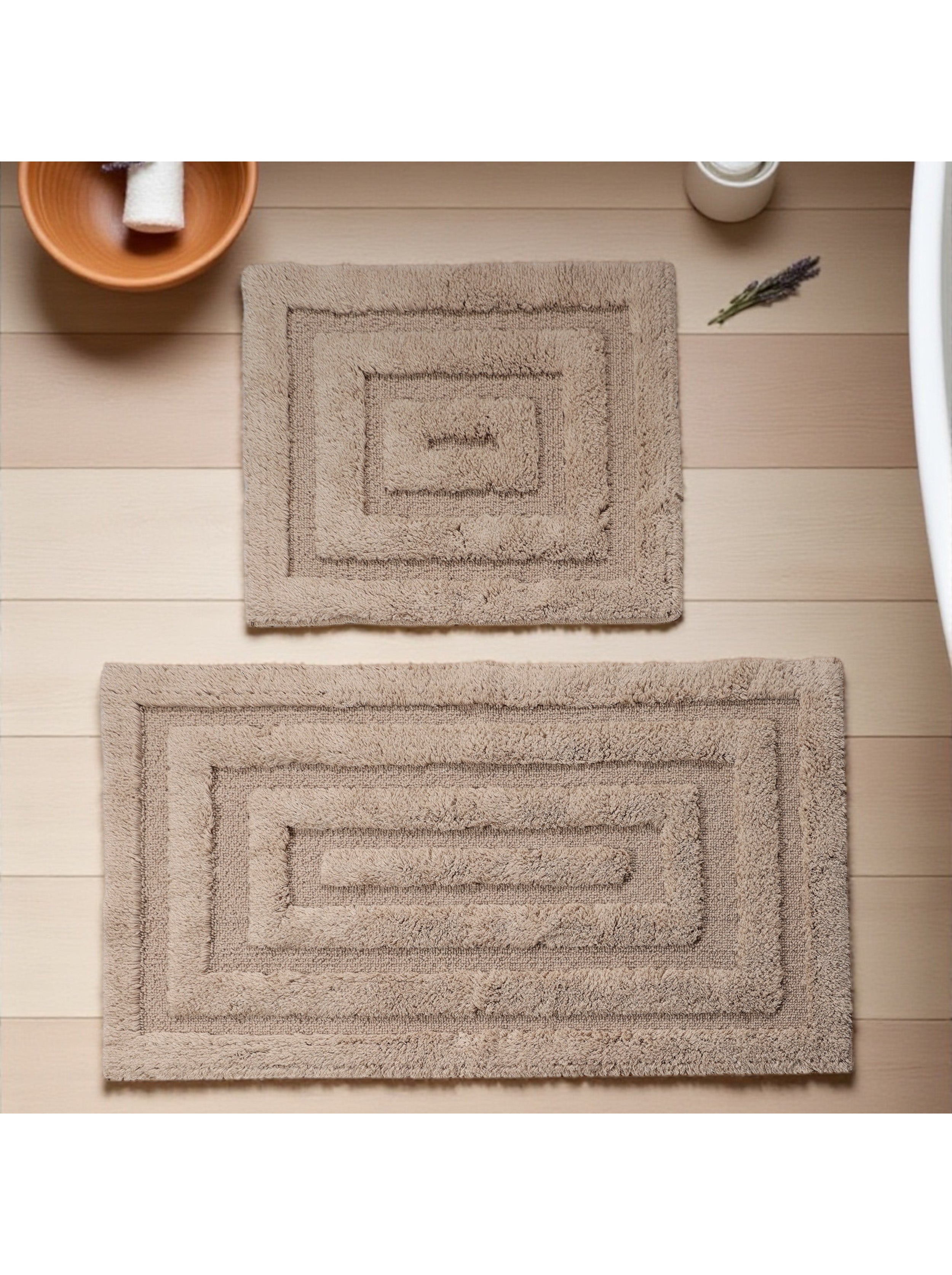 Deux tapis rectangulaires en tissu éponge beige avec un motif de rectangles concentriques sur un sol en bois clair