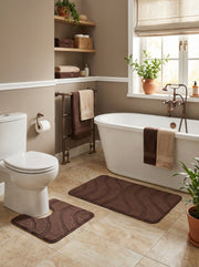 Deux tapis de bain marron foncé, l'un rectangulaire et l'autre en U, avec des motifs ondulés en relief sur un carrelage clair dans une salle de bain