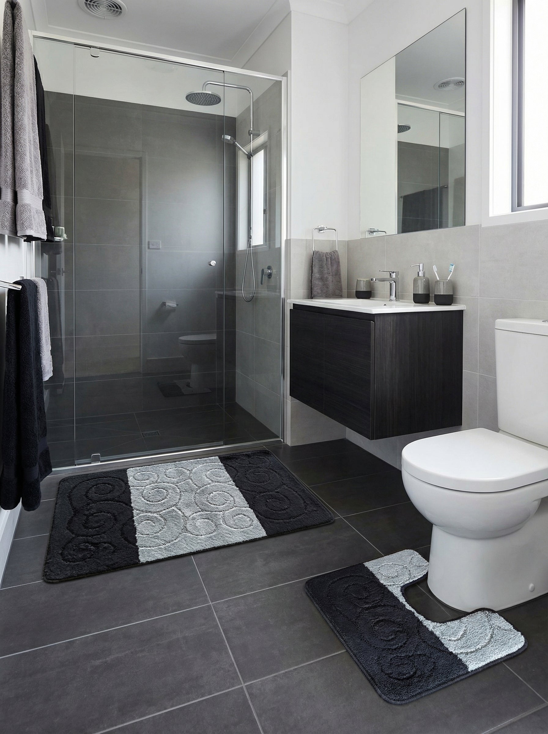 Tapis de bain doux et texturés, un rectangulaire et un en forme de U, bicolores noir et gris clair à motifs de volutes, dans une salle de bain moderne