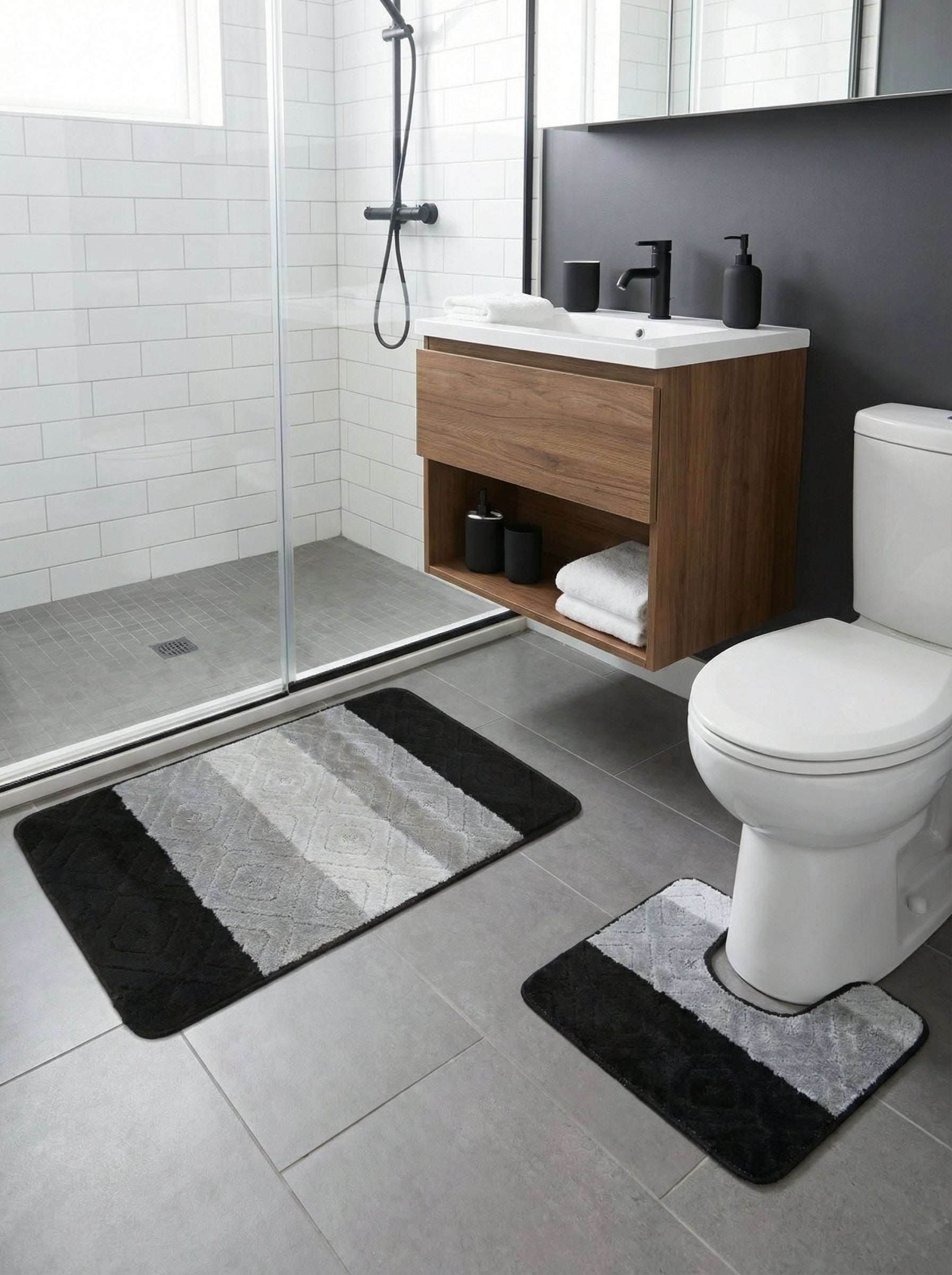 Lot de tapis de bain doux aux bandes noires, grises et blanches avec motifs losanges en relief, dans une salle de bain moderne