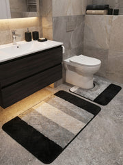 Tapis moelleux bicolore gris et noir, avec motifs losanges en relief et bandes diagonales, complété par un tapis contour de toilette assorti dans une salle de bain moderne