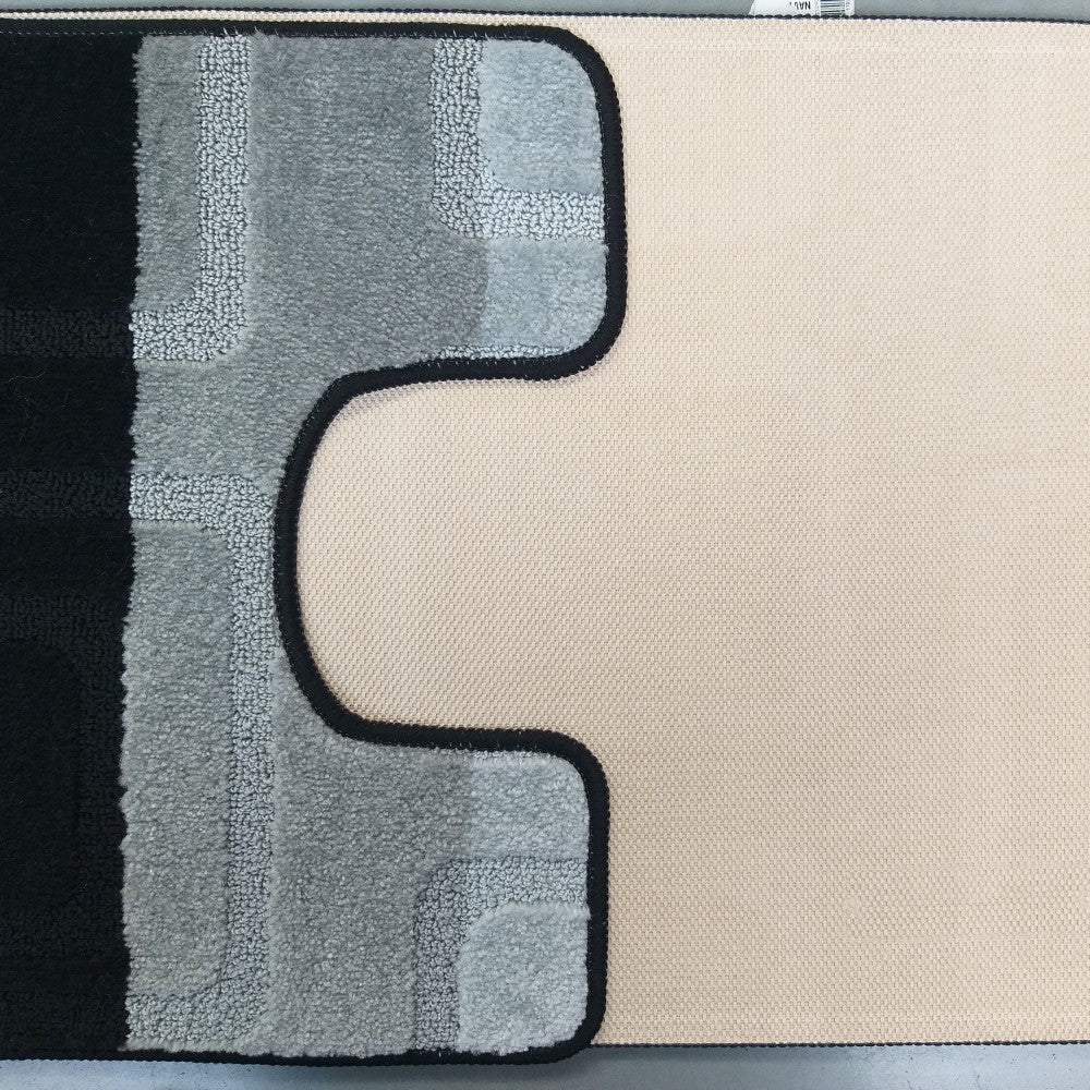 Tapis moelleux aux motifs géométriques noirs et dégradés de gris, au contour noir distinct, posé sur une surface textile beige