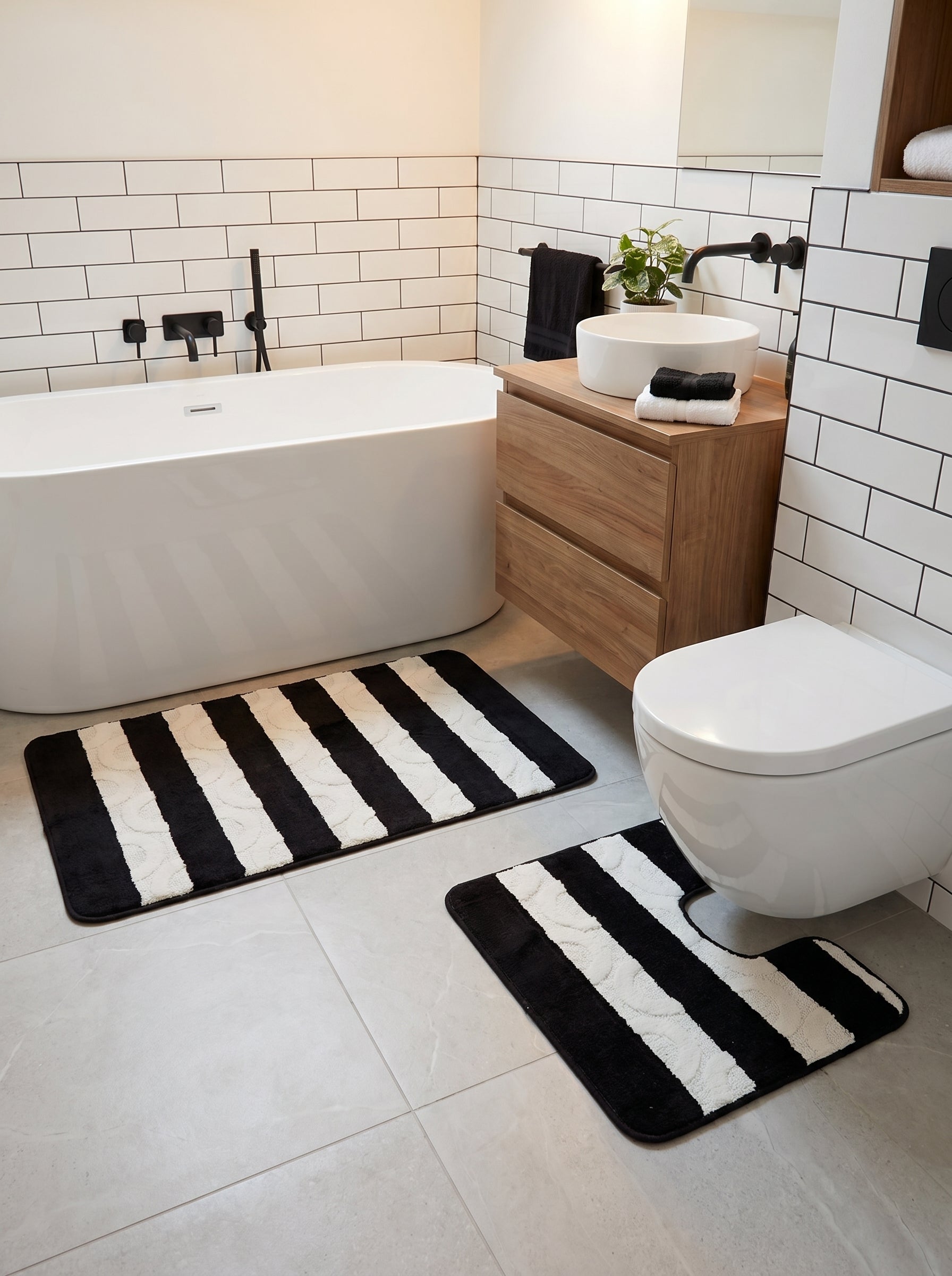 Ensemble de tapis de bain rayés noir et blanc avec des motifs en relief sur les bandes claires, un rectangulaire et un en U, dans une salle de bain