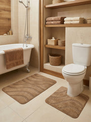 Deux tapis de bain beige-brun texturés à motifs de vagues, un rectangulaire et un en U, sur le carrelage clair d'une salle de bain