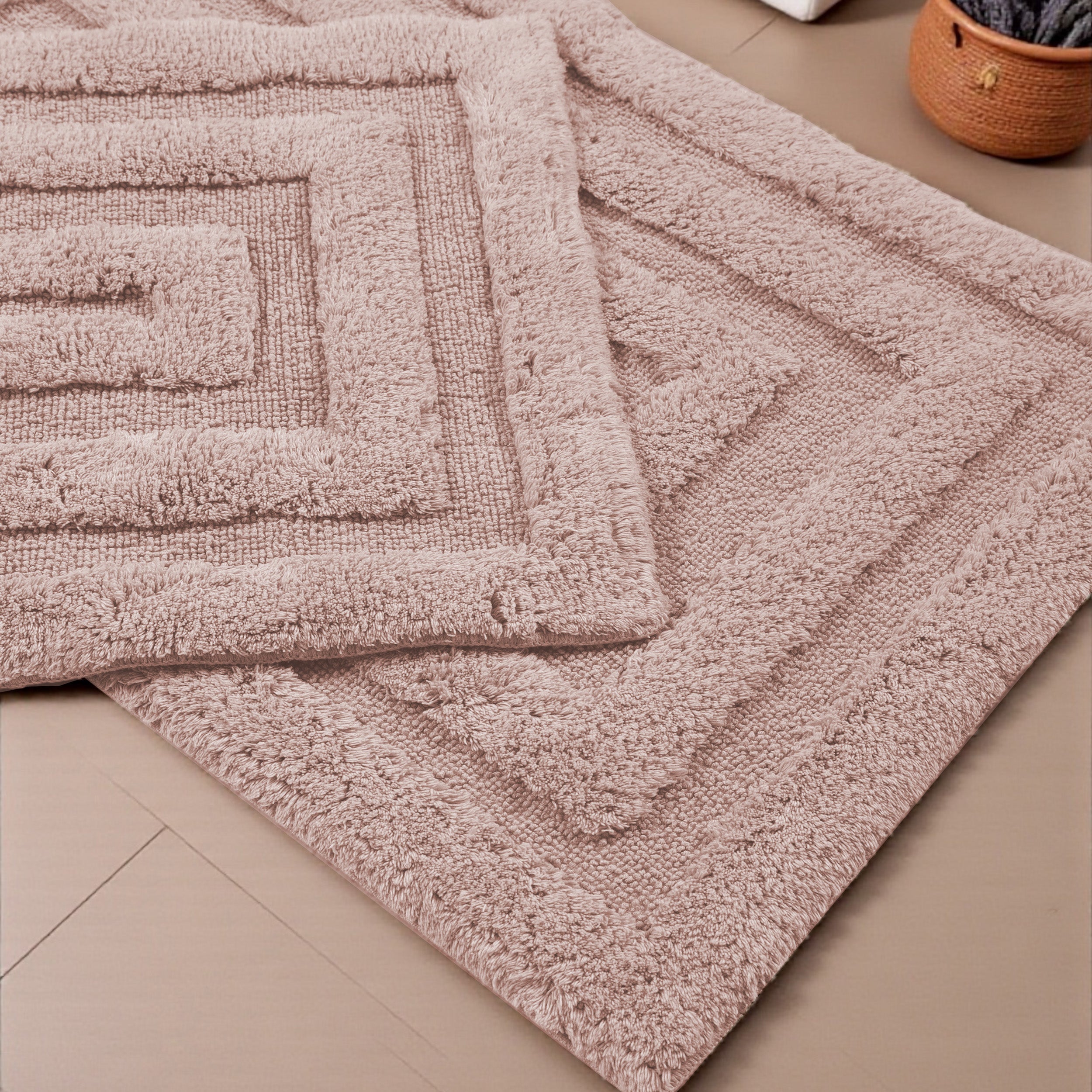 Deux tapis rose poudré à texture bouclée, avec un motif de carrés concentriques en relief, sur un sol carrelé