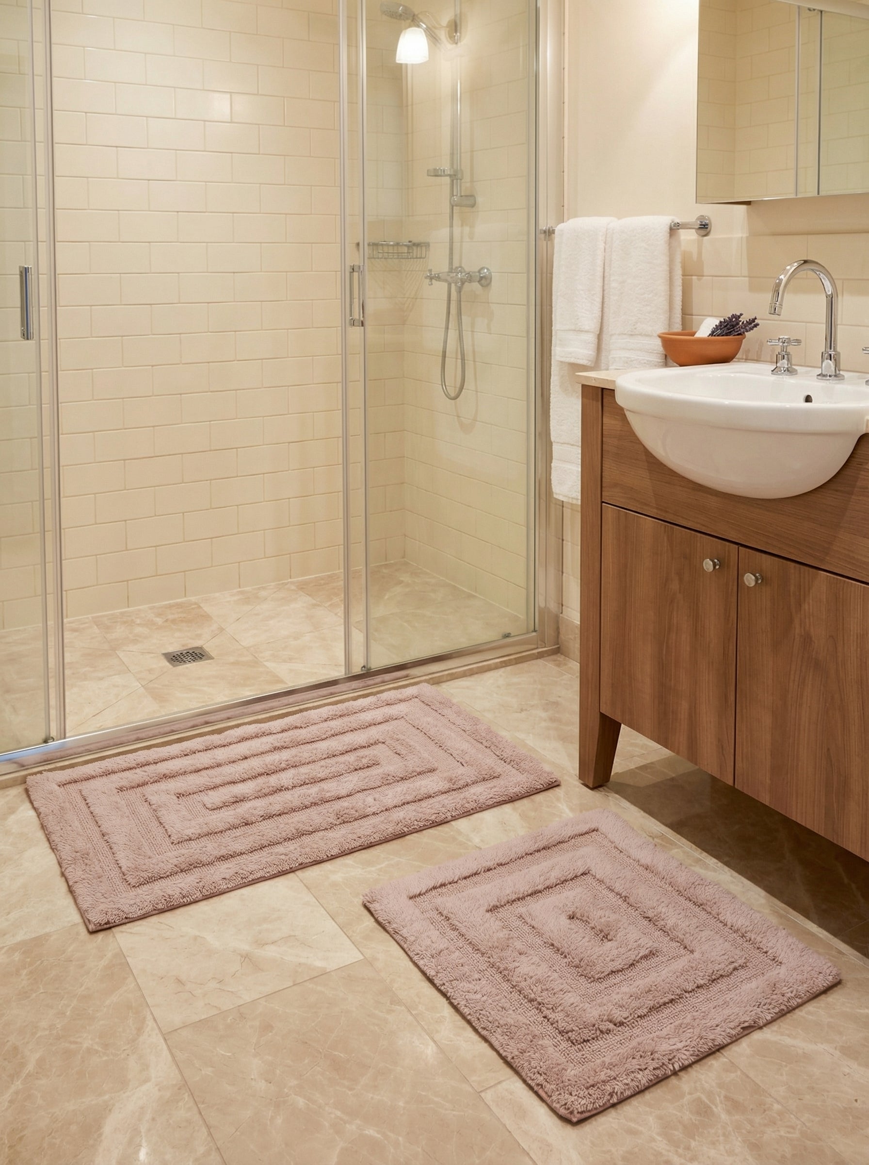 Deux tapis en coton rose poudré, rectangulaire et carré, avec motifs concentriques en relief, dans une salle de bain