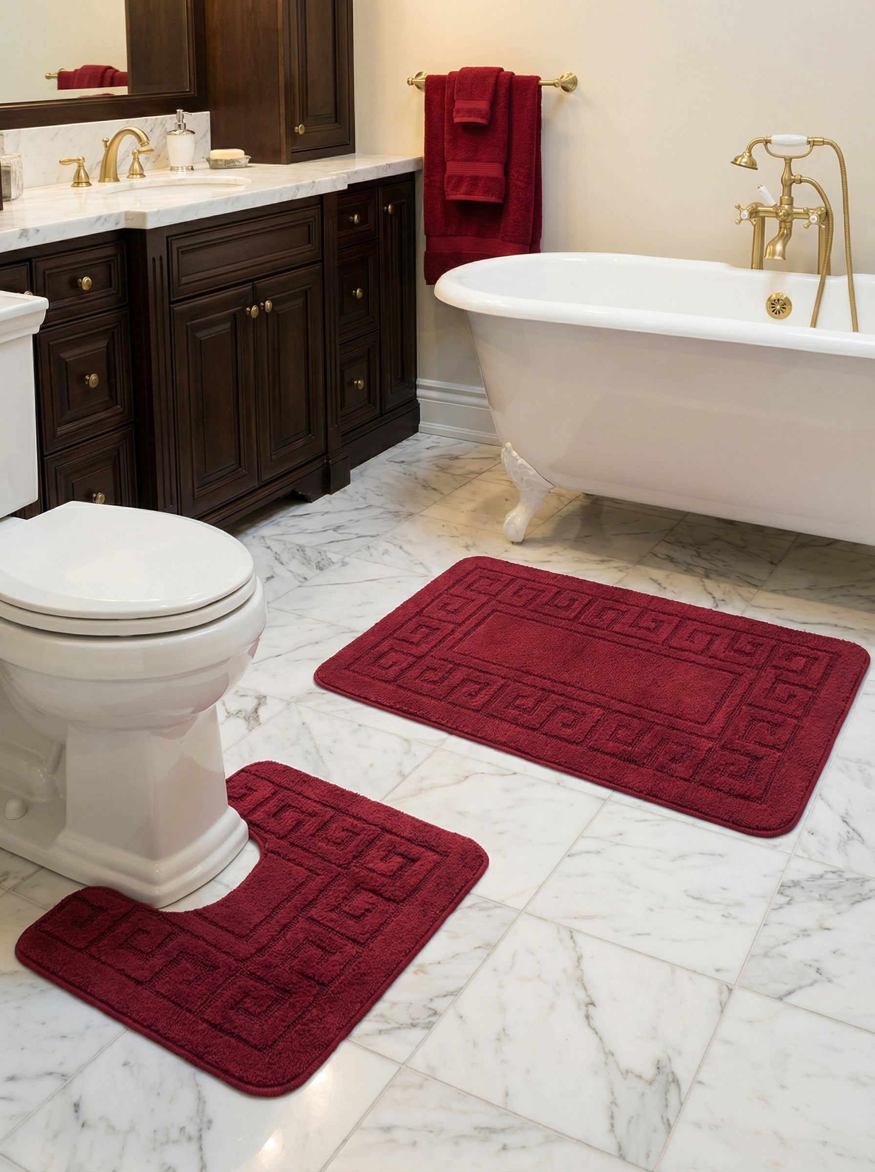 Deux tapis de bain bordeaux en éponge moelleuse, l'un rectangulaire l'autre en U, ornés d'un motif grec, dans une salle de bain
