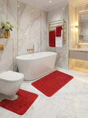 Tapis de bain rouges en tissu éponge avec motifs géométriques, un rectangulaire et un en U, sur sol marbré d'une salle de bain luxueuse