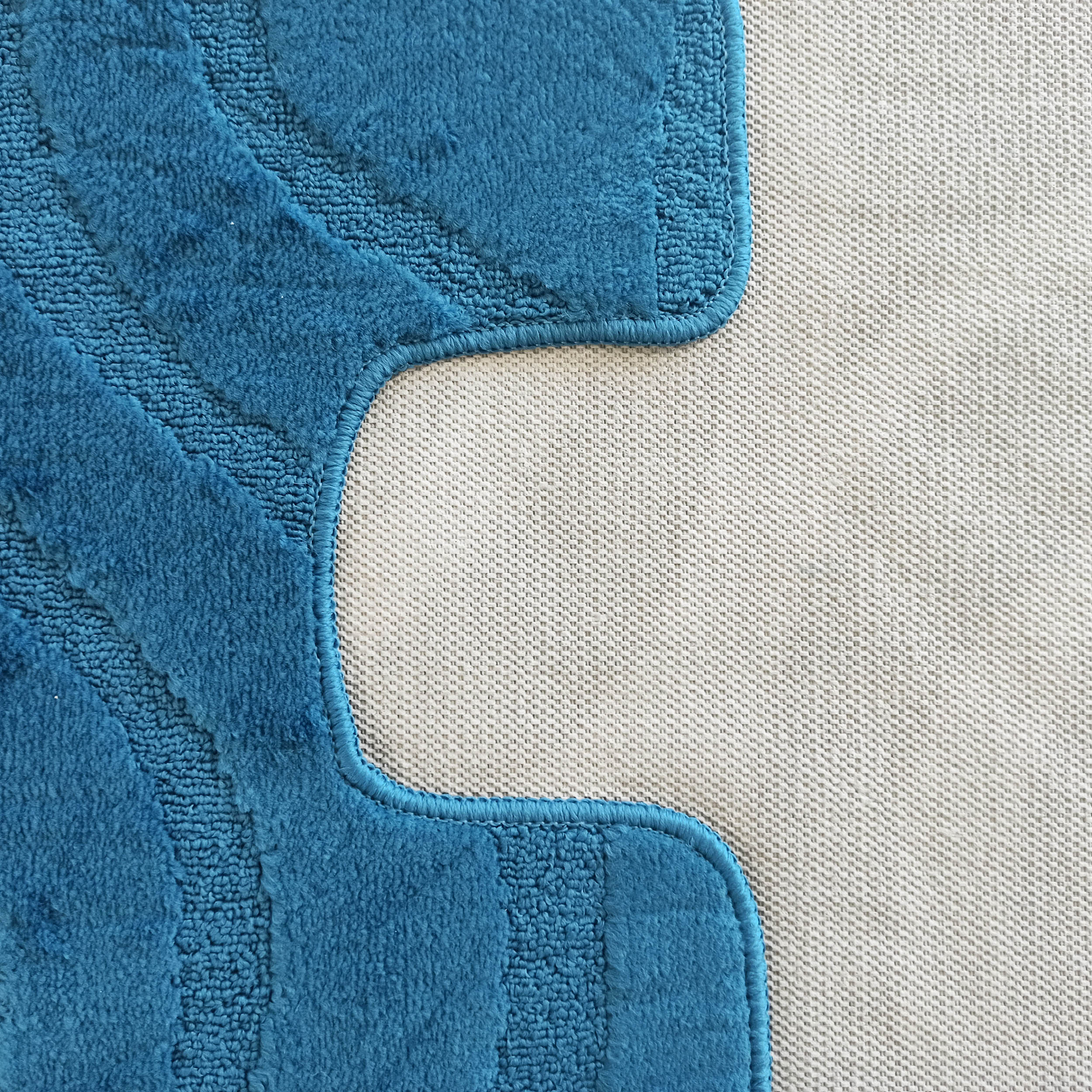 Tapis bleu turquoise moelleux avec motifs de vagues en relief, sur un fond beige clair tissé