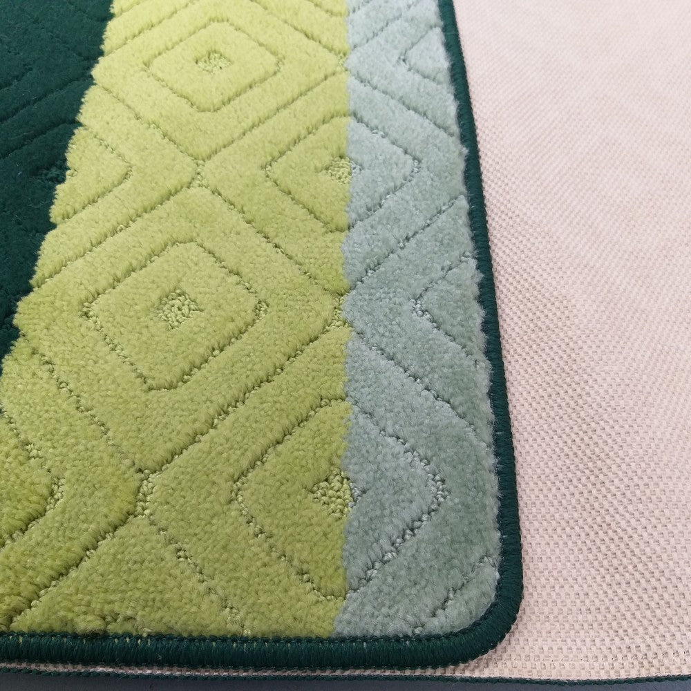 Tapis moelleux à bandes vert foncé, vert citron à losanges et vert d'eau à chevrons, le dos tissé beige du tapis est visible