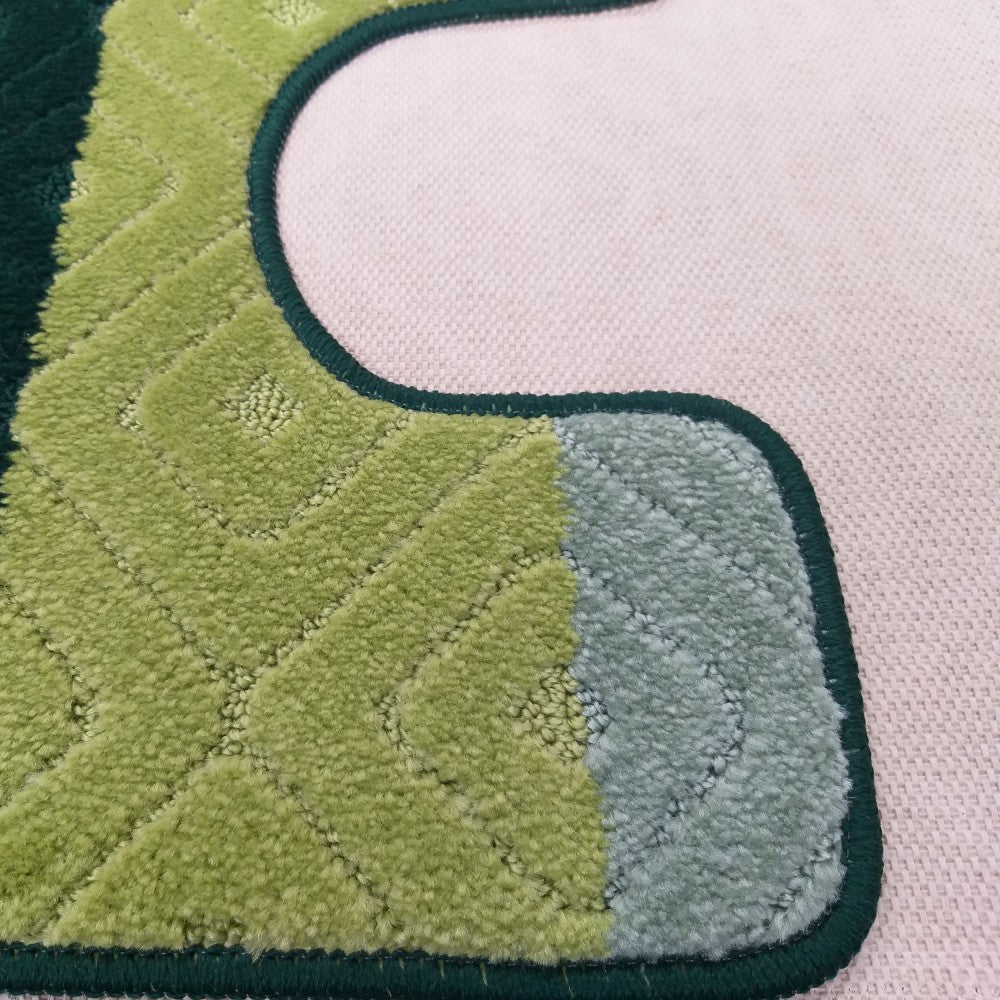 Tapis moelleux aux teintes vertes variées, avec des motifs de chevrons et de losanges, bordé de vert foncé